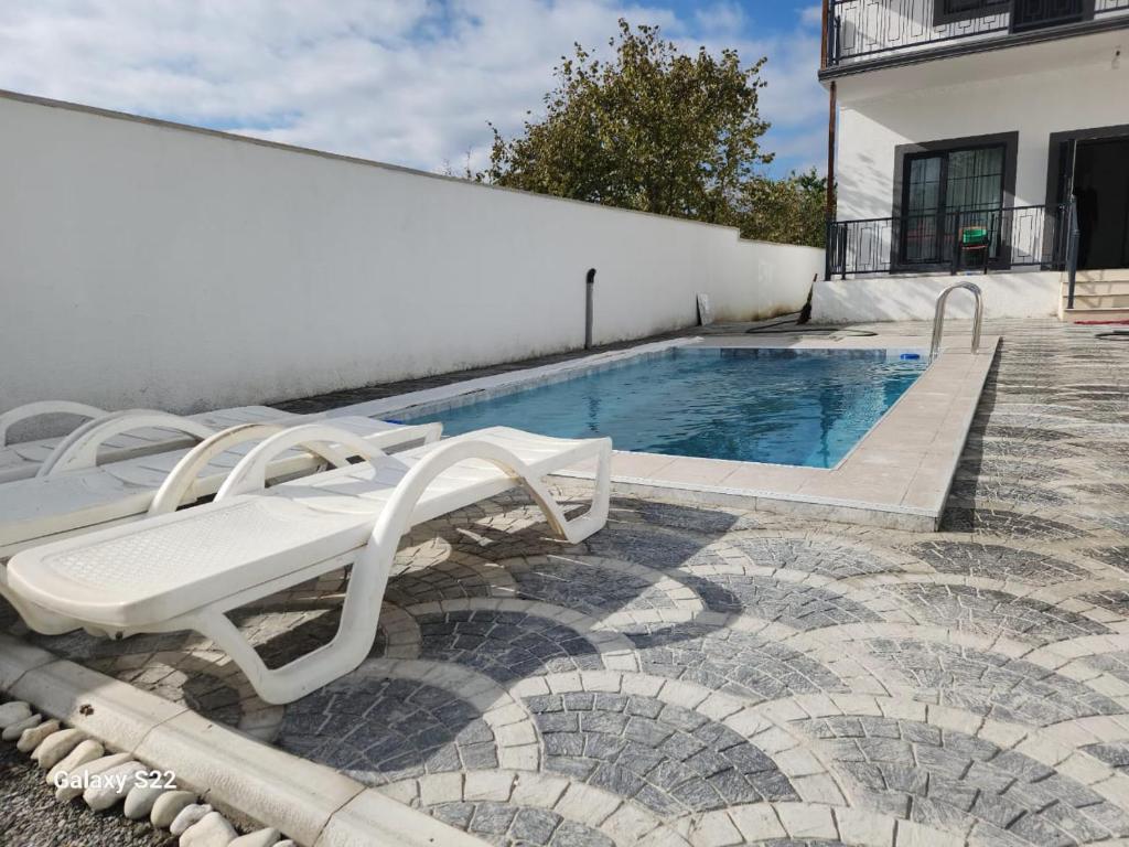 a pool with two lounge chairs next to a building at Ramalin evi in Quba