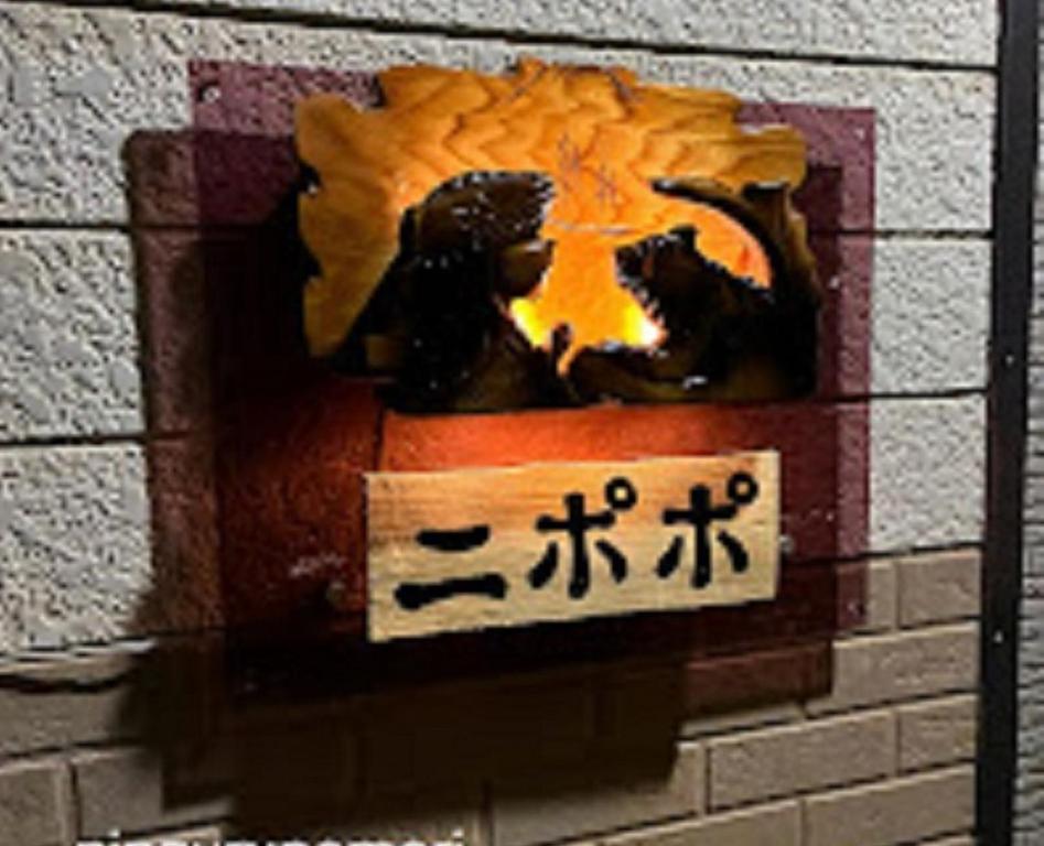 ein Schild an einer Backsteinmauer mit zwei Statuen darauf in der Unterkunft Minpakushisetsu Nipopo - Vacation STAY 19567 in Fukagawa