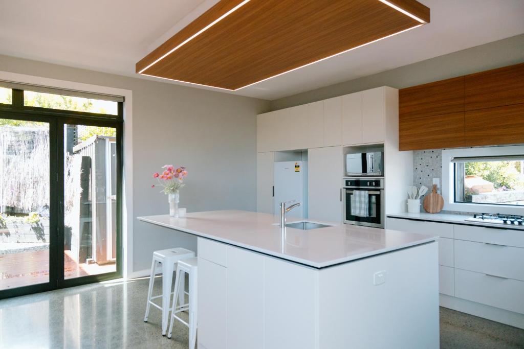 a kitchen with white counters and a large white island at Sunny and Modern Nelson Retreat with Designer Kitchen in Nelson