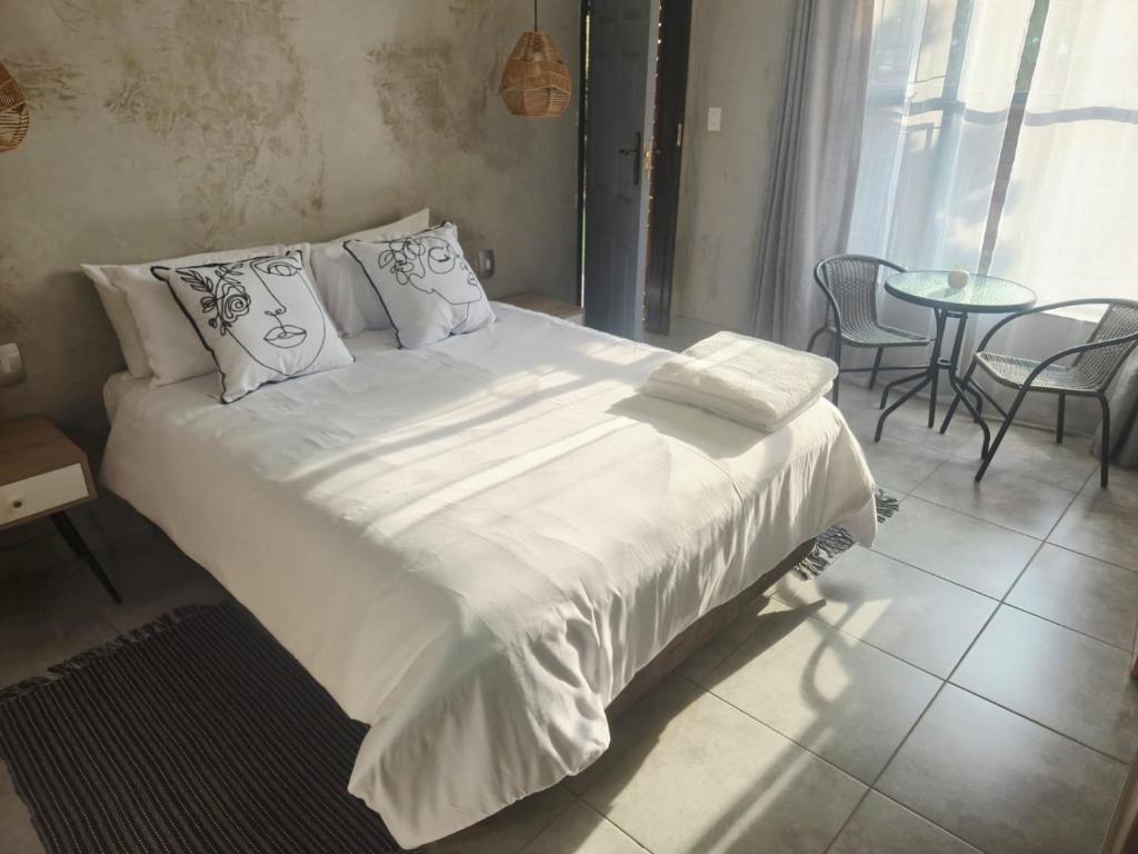 Una cama con sábanas blancas y almohadas en un dormitorio. en Roots of Grace, en Polokwane
