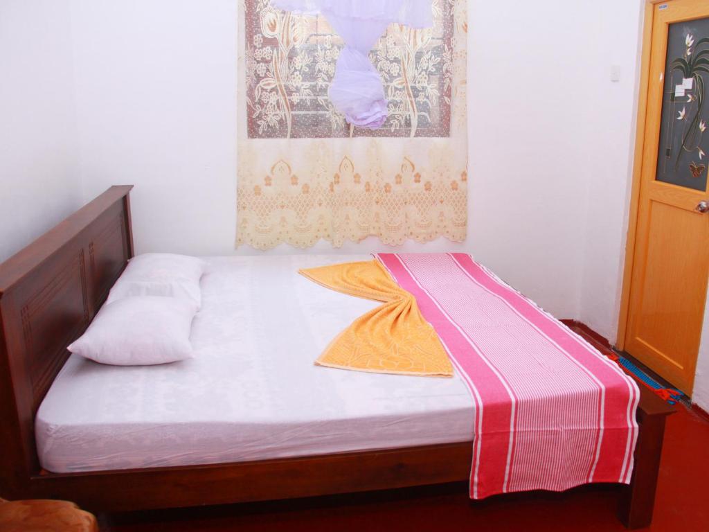 ein kleines Bett mit einer rosa und weißen Decke darauf in der Unterkunft Dilan Guest in Mirissa