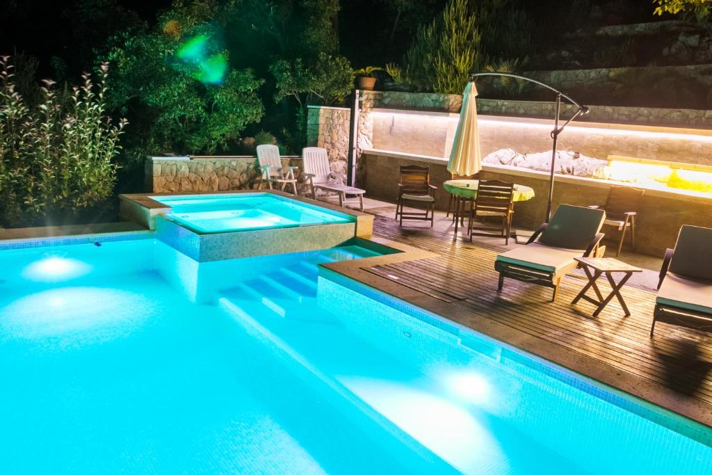 una piscina con sillas, una mesa y un patio en Villa Miolin, en Trpanj