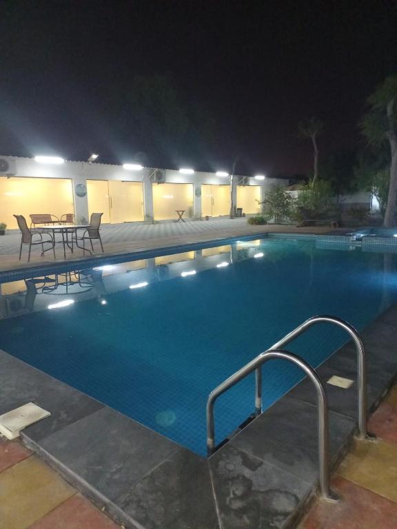 a swimming pool at night with a table and chairs at إستراحة الريف in Kalbā