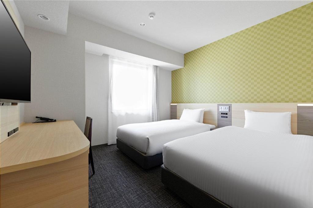 Postel nebo postele na pokoji v ubytování Sotetsu Fresa Inn Osaka Namba