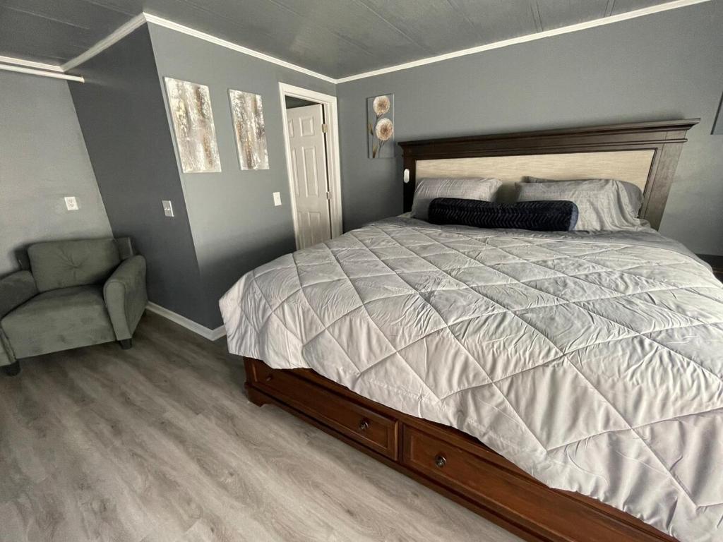 een slaapkamer met een groot bed en een stoel bij Lake House Hide Away in Roxboro