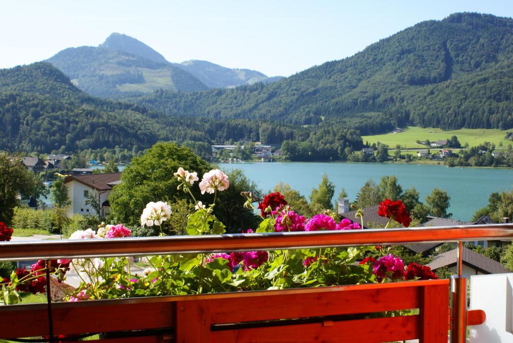 a balcony with flowers and a view of a lake at Haus Bergblick in Fuschl am See