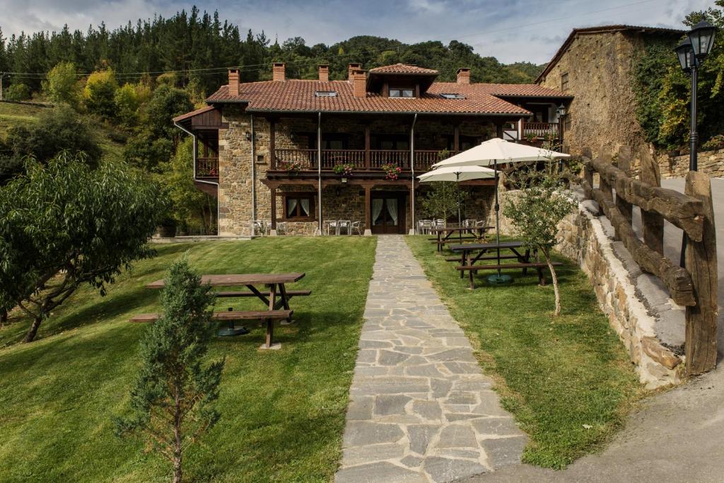 una casa con una mesa de picnic y bancos frente a ella en La Dobra de liebana, en Cambarco