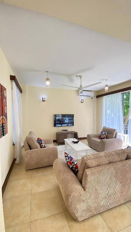 a living room with two couches and a tv at AfroHaki Homes in Mombasa
