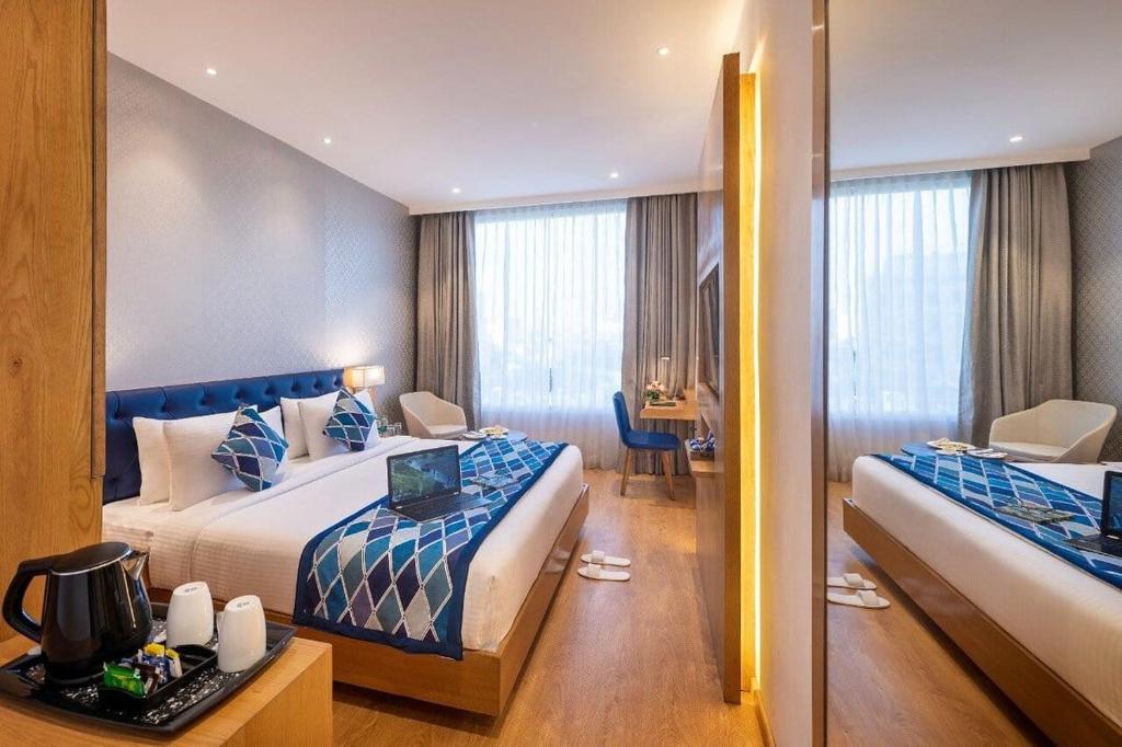 a hotel room with two beds and a desk with a laptop at hotel Linda Grand Near Delhi Airport, A Block road no 6 street No 12 Mahipalpur New Delhi in New Delhi