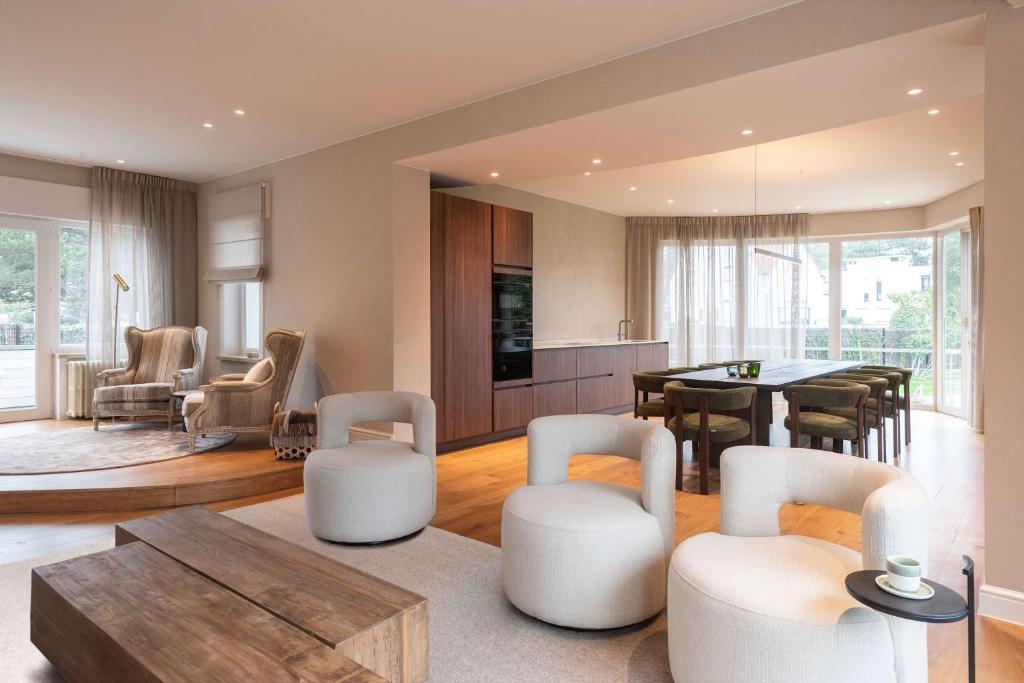 un salon avec des chaises blanches et une table dans l'établissement De Pagode - A Serene Coastal Home with Pool, à Duinbergen