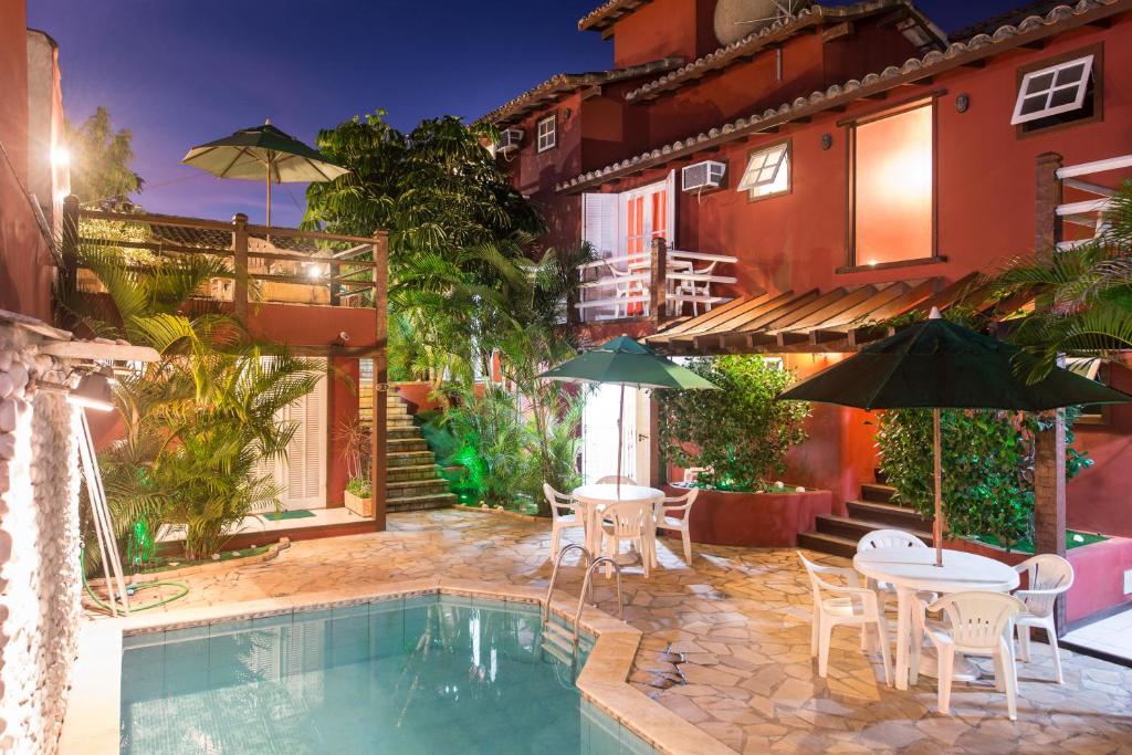 a house with a swimming pool with tables and umbrellas at Meu Sonho Búzios in Búzios