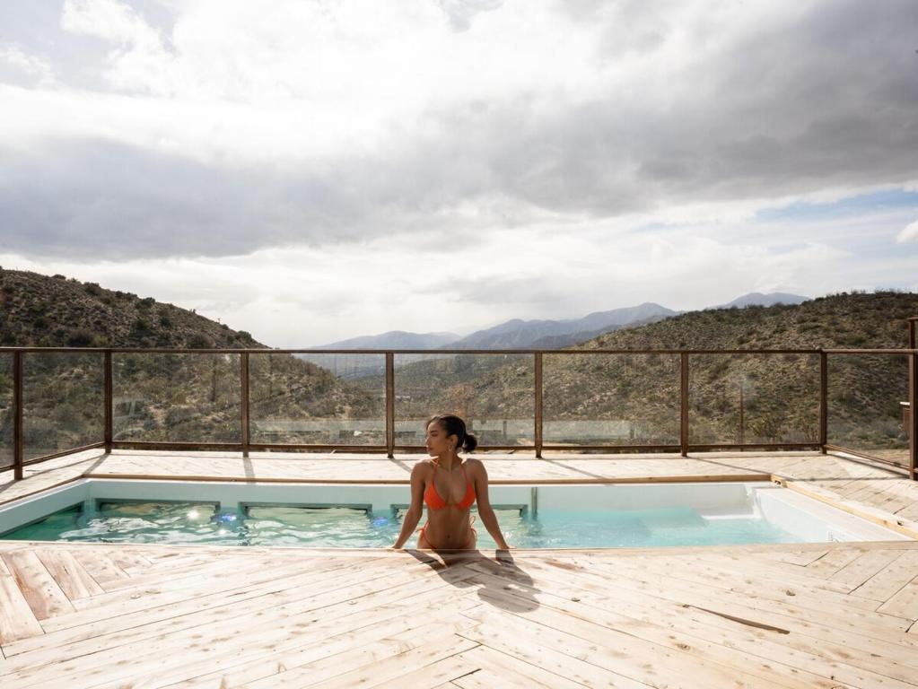 a woman in a bikini sitting in a swimming pool at Mountain Views, Pool, Spa & Serenity Stargate in Yucca Valley