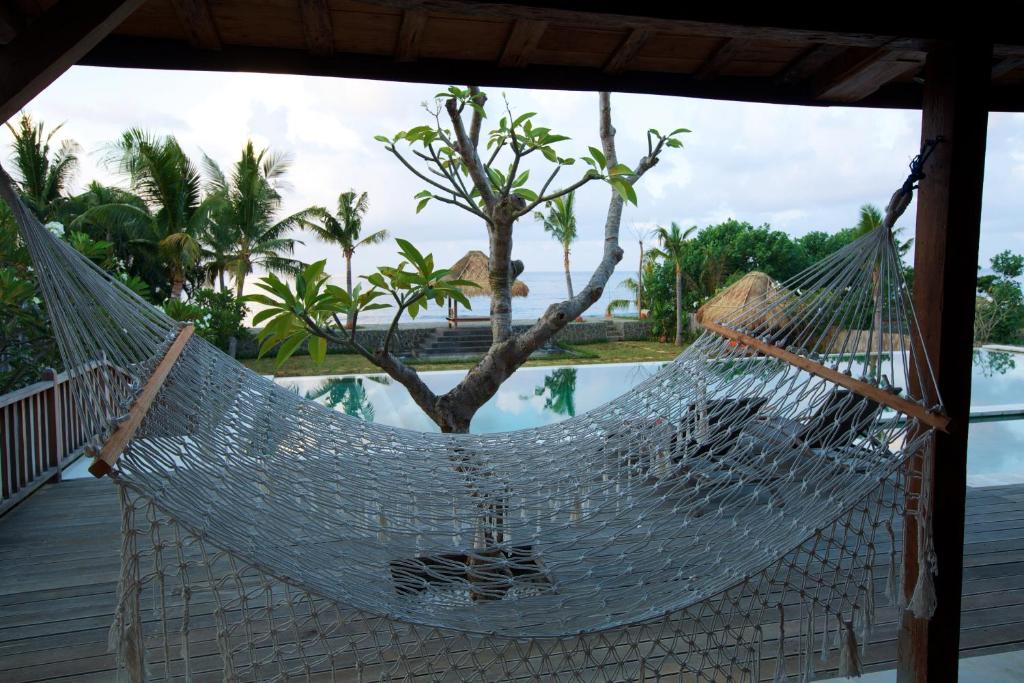 a hammock on a porch next to a pool at The Kampung in Amed