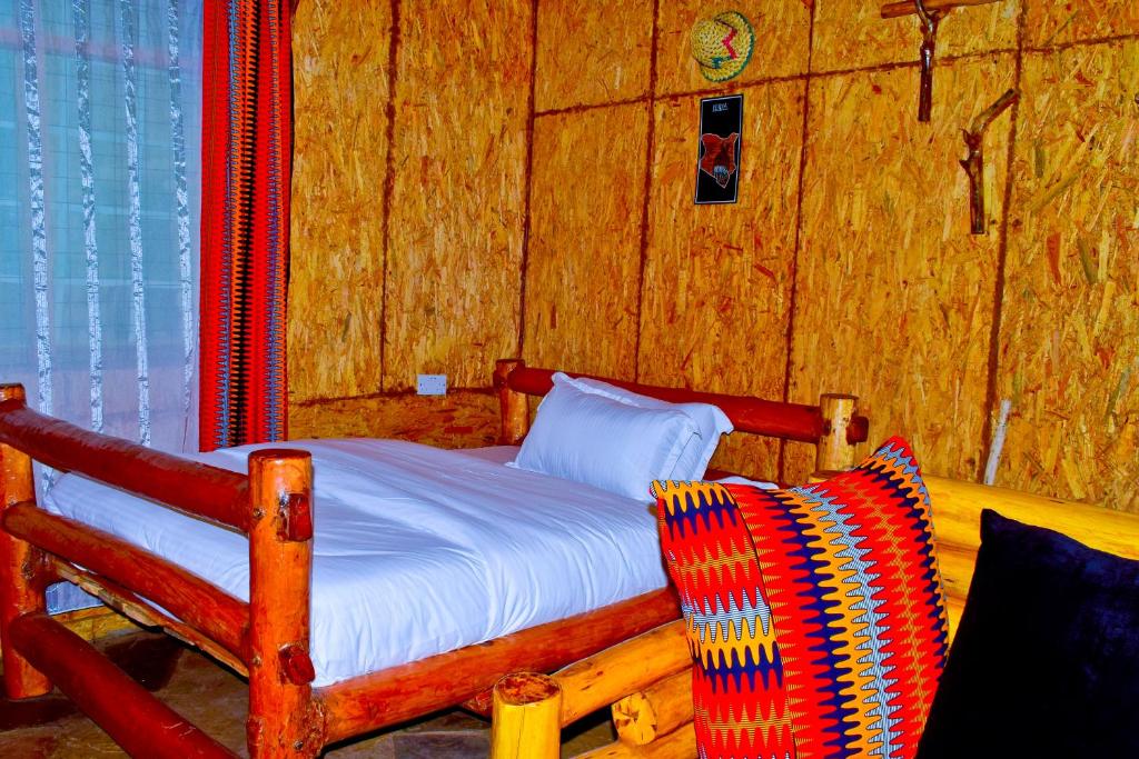 Hakuna Matata Gardens في Migori: غرفة نوم بسرير خشبي وكرسي