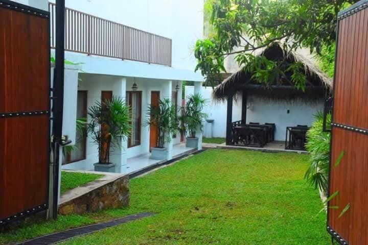 a courtyard of a house with a grass yard at Tikla safari lodge in Udawalawe