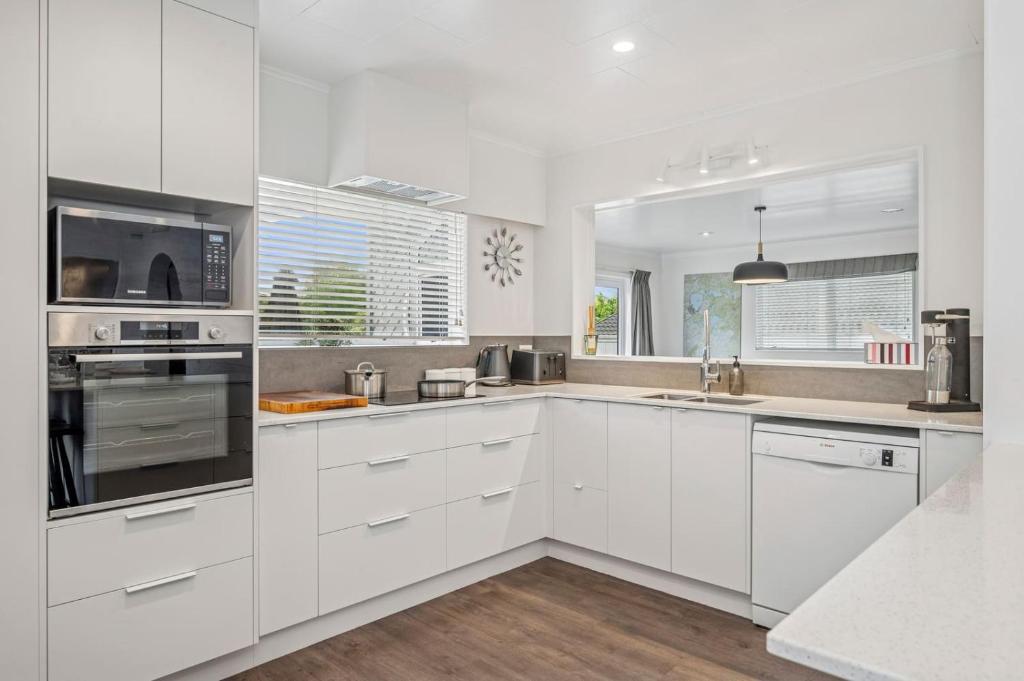 een witte keuken met witte kasten en apparaten bij Tihi Time - Great Deck Spa Pool & Games Room in Rotorua