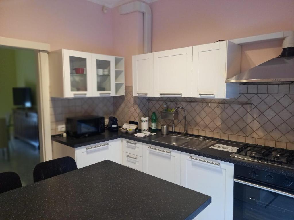 Una cocina con gabinetes blancos y una encimera negra. en La casa del nespolo, en Massa