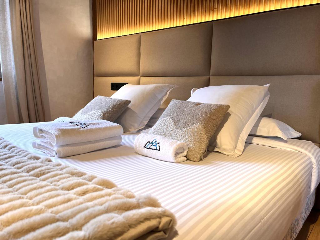 a bed with white pillows and towels on it at AC Apartaments Tarter Chalet in El Tarter