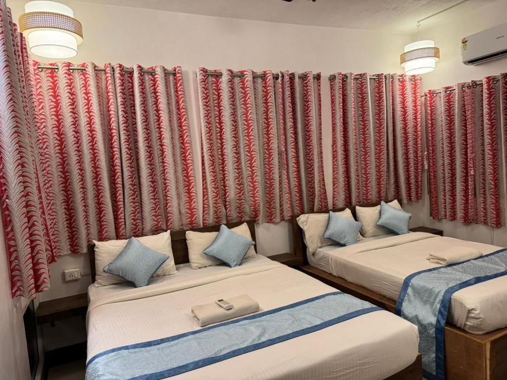 two beds in a room with red curtains at De Pondy beachside Villa in Virāmpattinam
