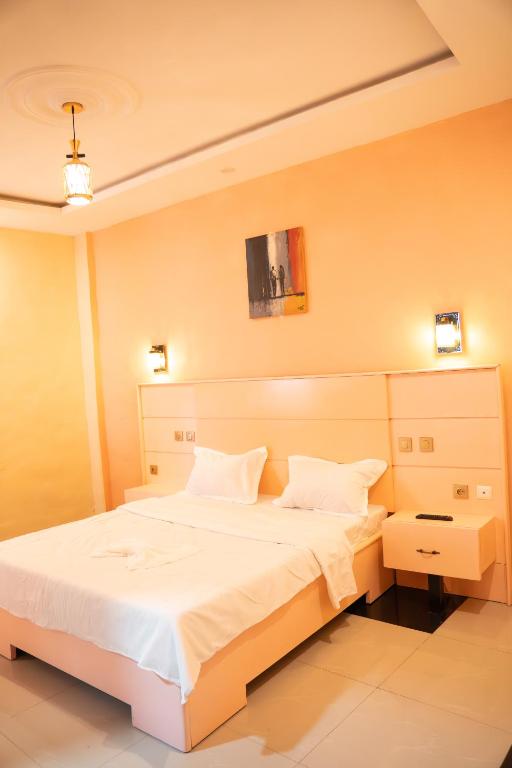 BafoussamHÔTEL Michou的卧室里有一张大床，床单和枕头都是白色的