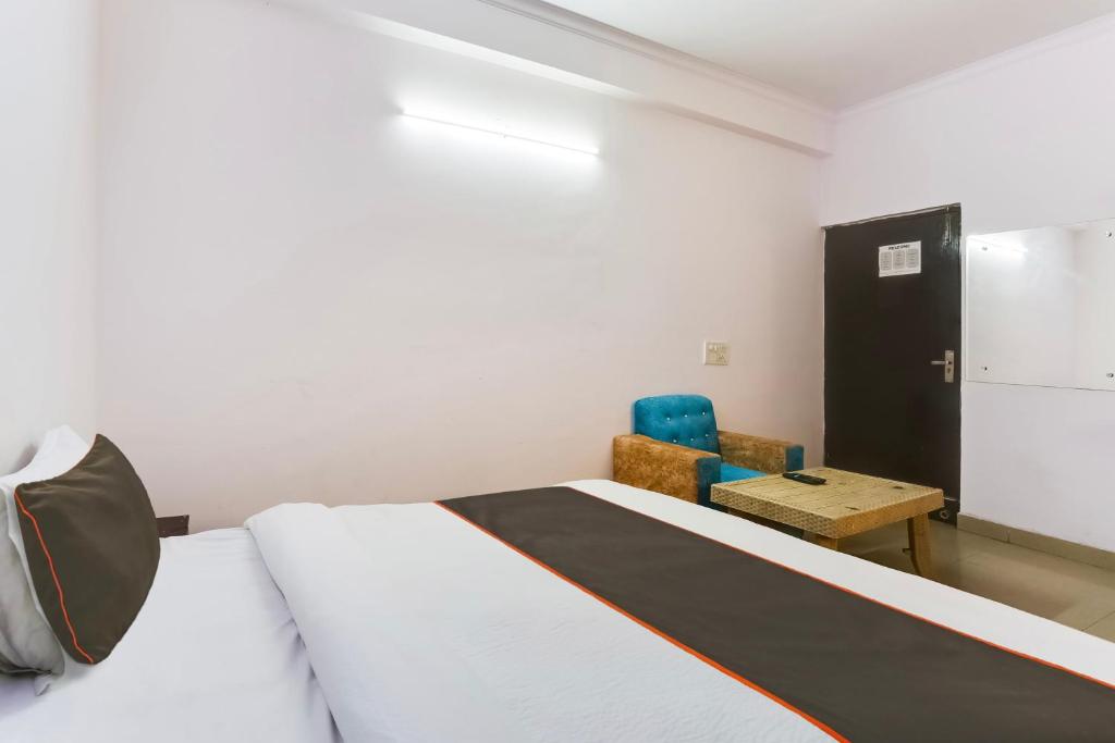 a bedroom with a bed and a blue chair at Hotel O Happy Residency in New Delhi