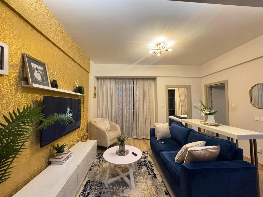 un soggiorno con un divano blu e una TV di Elite Residence a Nairobi