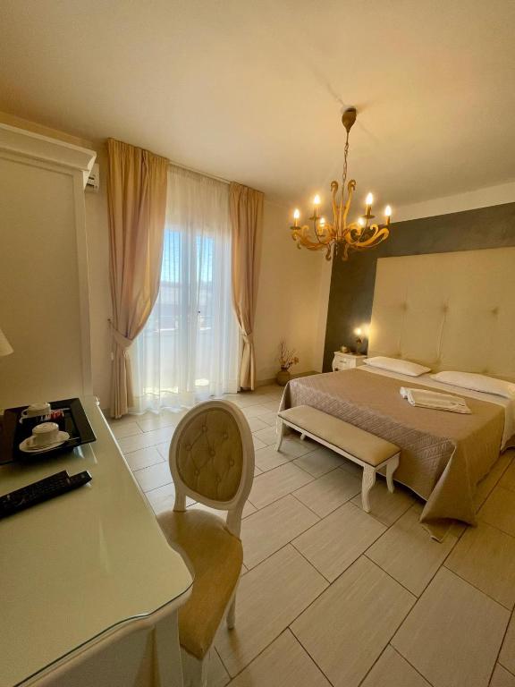 una grande camera da letto con un letto e un lampadario a braccio di Apparthotel Angela ad Alezio