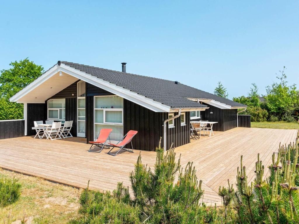 een huis met een terras en stoelen erop bij 6 person holiday home in Løkken in Løkken