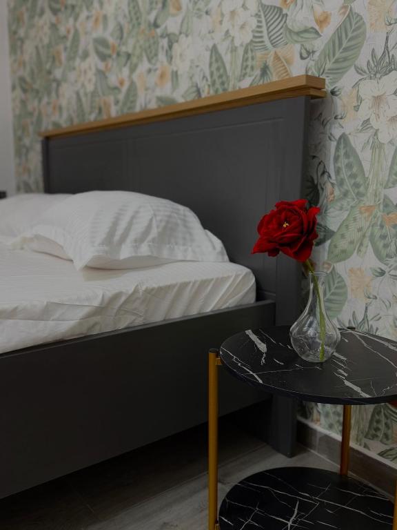 克拉约瓦Petra's的一间卧室配有一张床,一个花瓶上放着玫瑰花