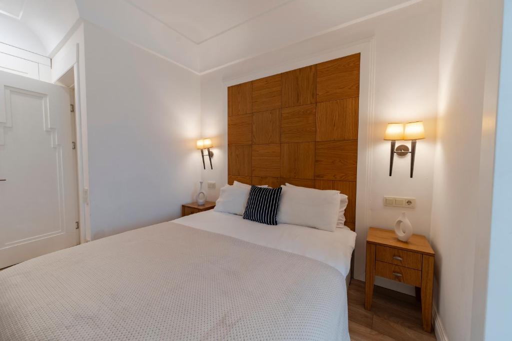 een slaapkamer met een wit bed en een houten hoofdeinde bij Central 3-Bedroom Apartment with Balcony and Elevator in Istanbul
