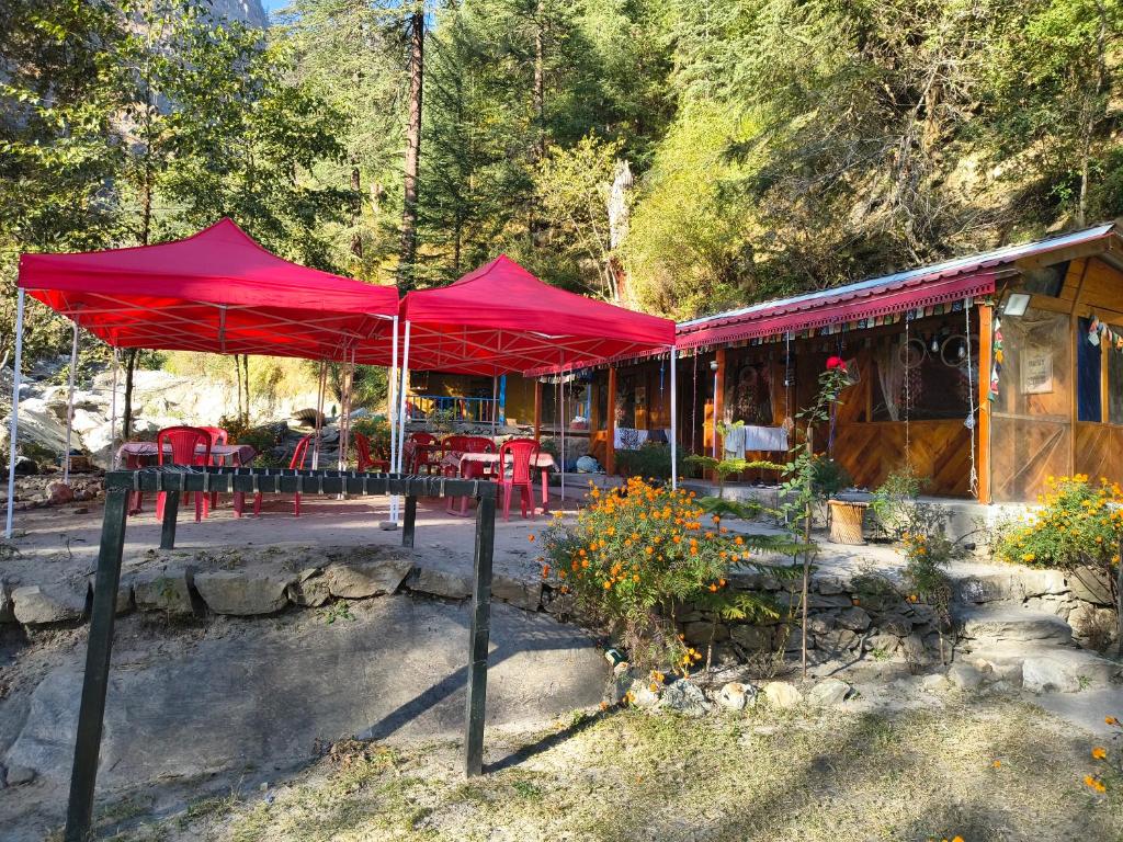 un ristorante con ombrelloni rossi di fronte a un edificio di Shanti People Huts And Cafe a Kasol