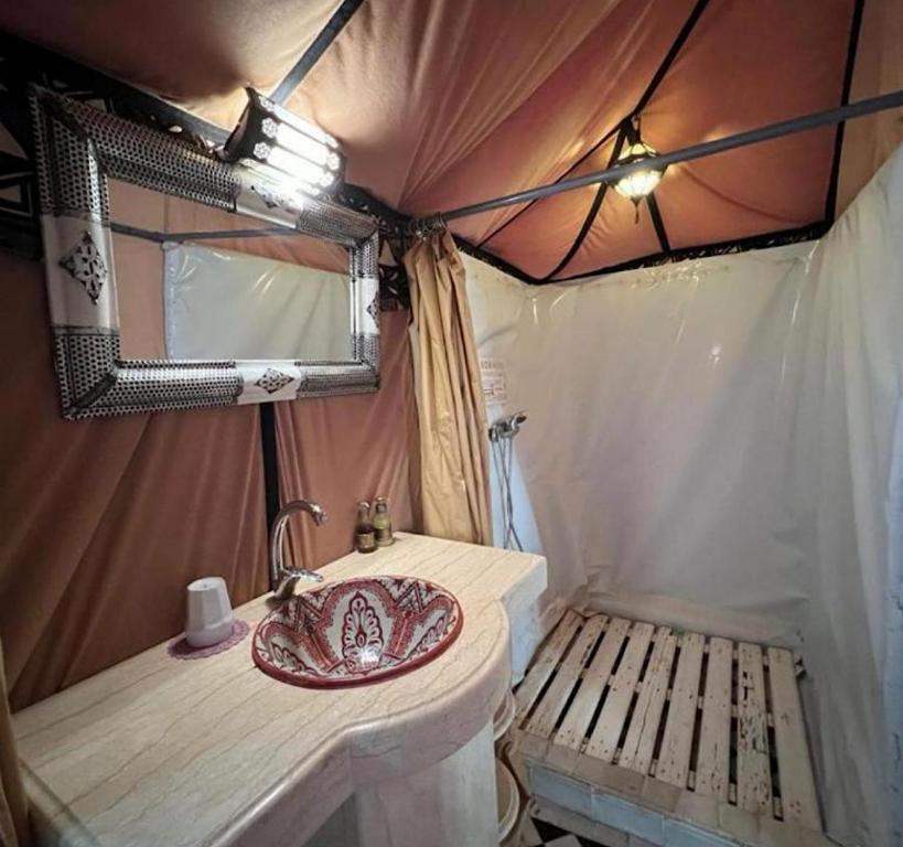 a bathroom with a sink and a bench in a tent at Unique Luxury Camp in Merzouga
