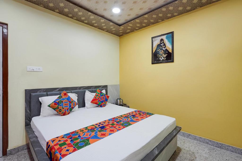 a bedroom with a bed and a yellow wall at FabHotel Shivkashi Inn - Dasaswamedh Ghat in Varanasi
