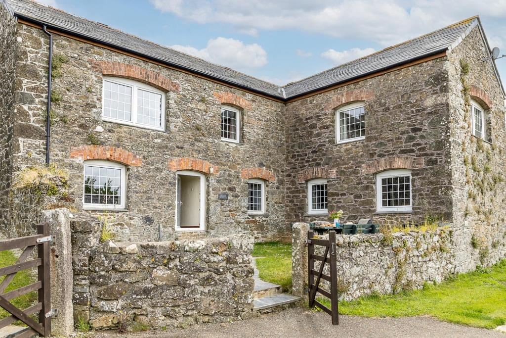 an old stone house with a stone wall at Cherry Cottage in Saint Endellion