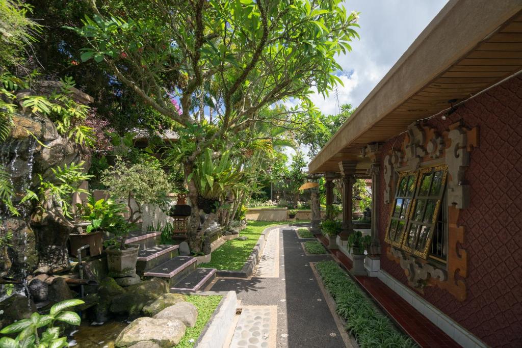 un jardín fuera de una casa con árboles y un edificio en Nuaja Balinese Guest House en Ubud