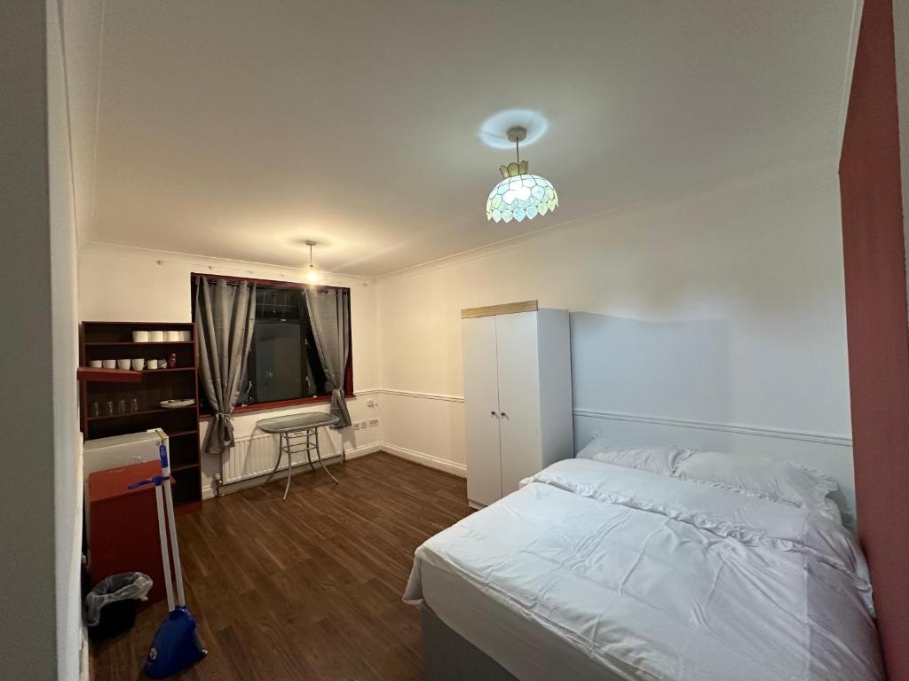 une chambre avec un lit blanc et une télévision dans l'établissement B&A House, à Romford