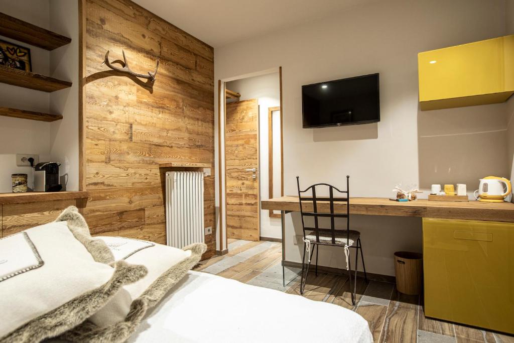 een slaapkamer met een bed en een bureau met een televisie bij L'Atelier du Temps - Maison Ida in Courmayeur