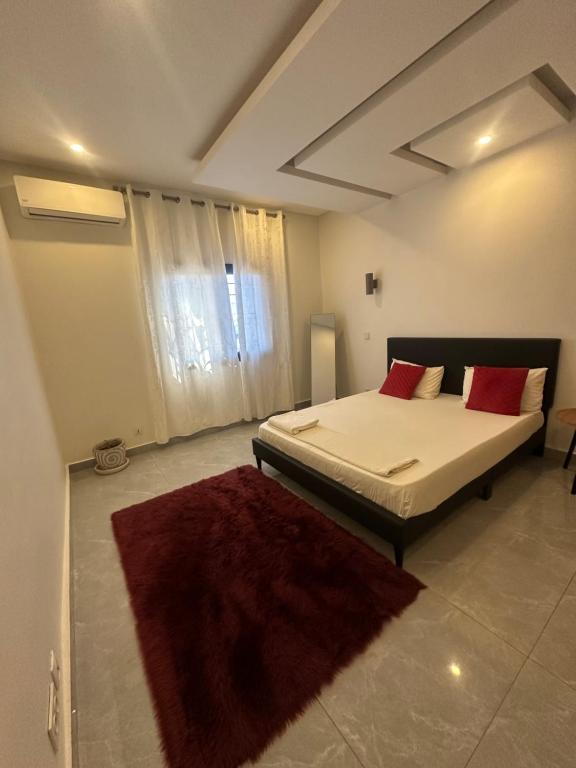 a bedroom with a bed and a red rug at Chambre climatisée ou ventilée à Dakar in Dakar