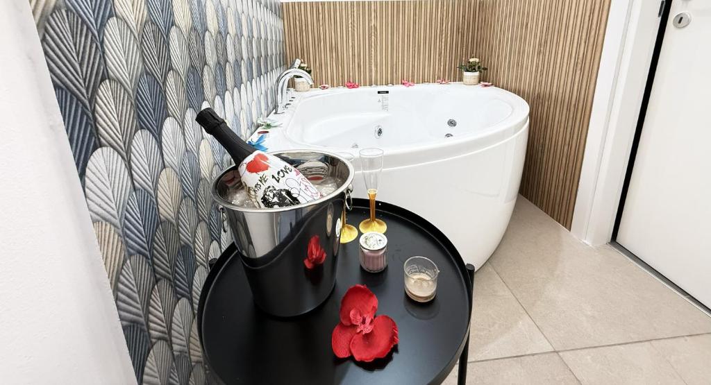 ein Badezimmer mit einer Badewanne und einem Tisch mit einer Flasche Champagner in der Unterkunft B&B Ovidio in Catania