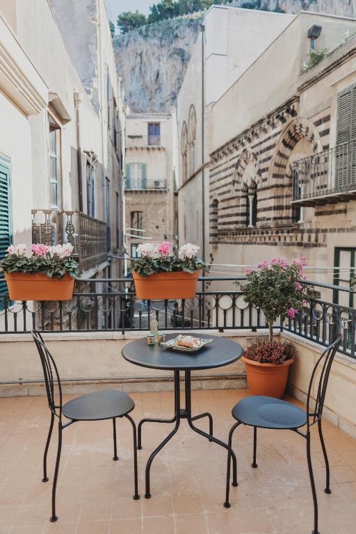 a table and chairs on a balcony with flowers at Dimora le Due Sicilie in Cefalù
