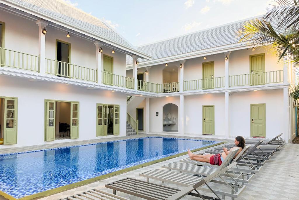 琅勃拉邦White Elephant Hostel的一位女士坐在游泳池边的椅子上