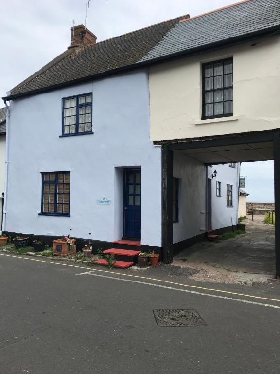 a white house with a red bench in front of it at Pier Cottage in Watchet