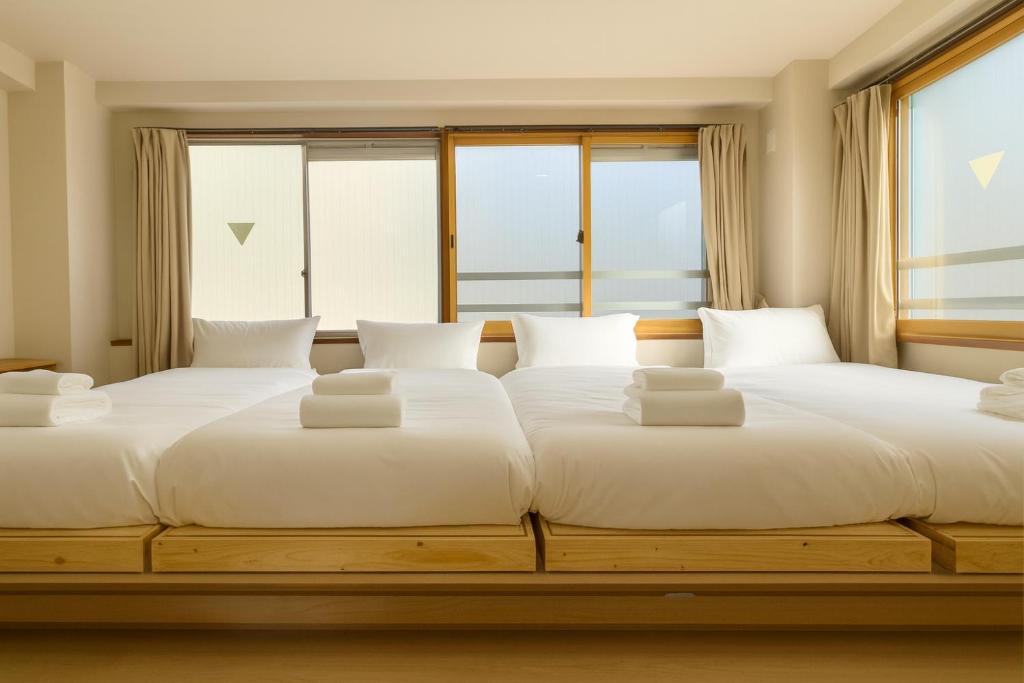 2 Betten in einem Zimmer mit Fenstern in der Unterkunft Ikeda Ueno 501 Quad room Room in Tokio