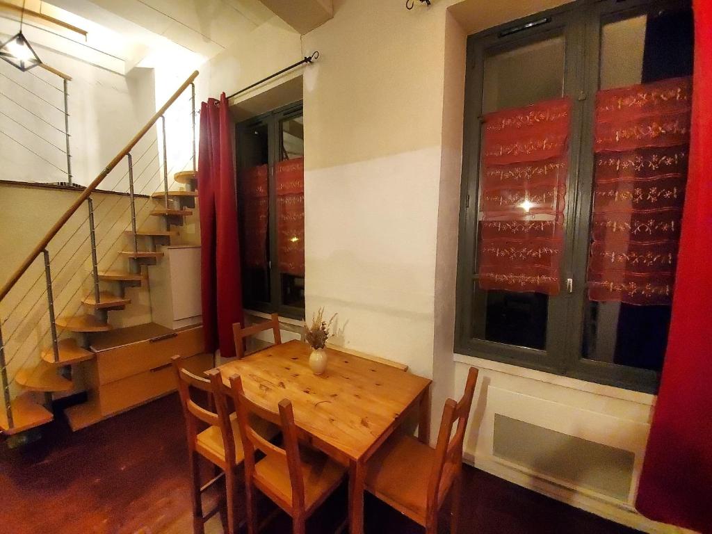 a dining room with a wooden table and a staircase at Le nid de la ferme du plan in Froges