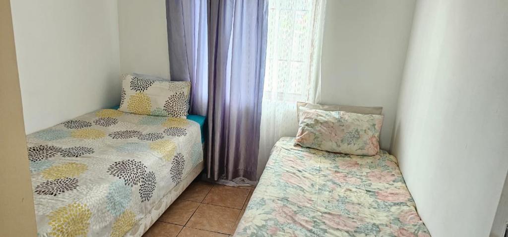 a small bedroom with a bed and a window at Ingeyethu Guest House in Umlazi