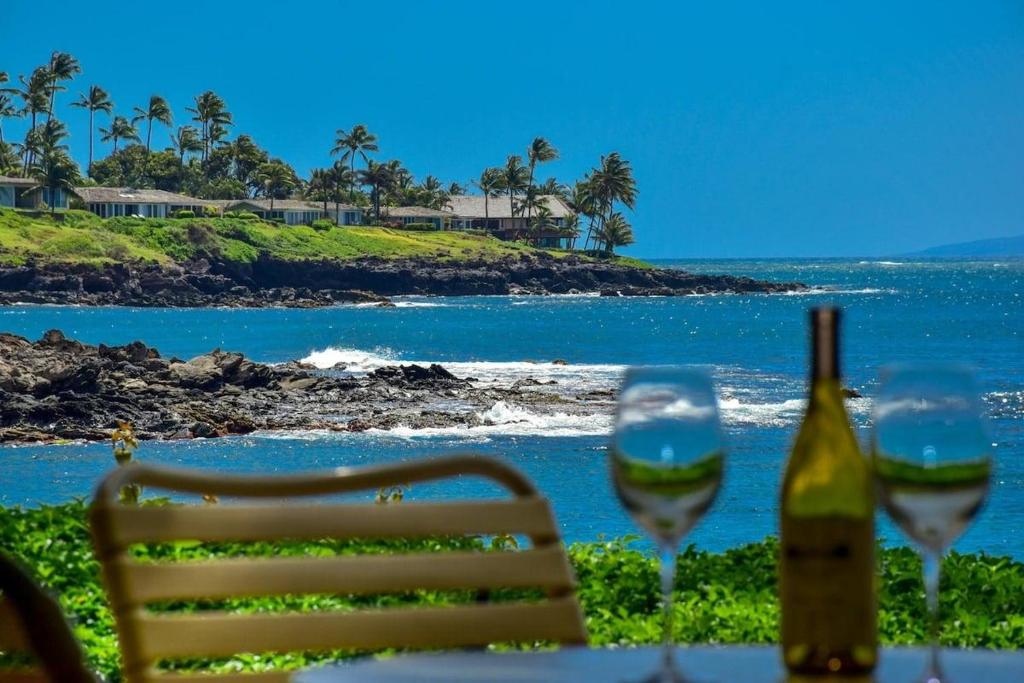 Una mesa con una botella de vino y dos copas. en Napili Point A8 · NP A8 OceanFront 1BD Condo w Ocean Views AC Po, en Kahana