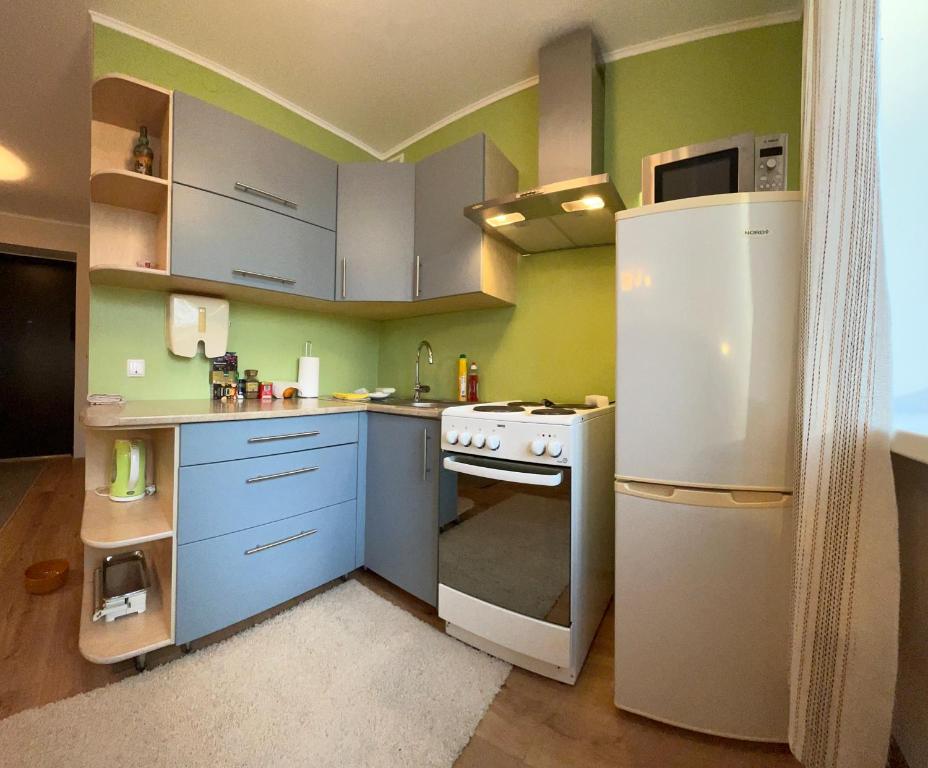 a kitchen with blue cabinets and a white refrigerator at Уютная квартира в 10 минутах от моря in Aseri
