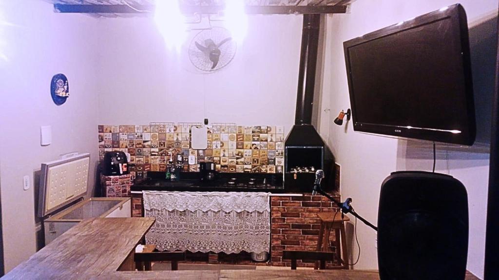 a living room with a table and a large television at Ares da Bocaina Suítes in Bananal