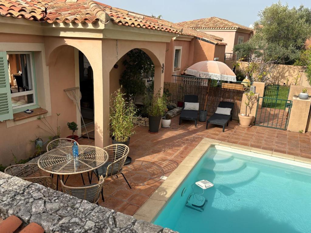 a backyard with a swimming pool and a patio with a table at vue sur le golfe de Saint Florent in Saint-Florent