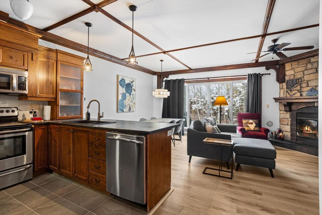 eine Küche und ein Wohnzimmer mit einem Herd und einem Sofa in der Unterkunft Les Manoirs Wpool & Hot Tub Near Village 120-7 in Mont-Tremblant